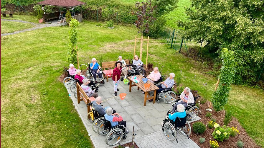 Vogelperspektive auf die Senior*innen beim Koordinationsspiel auf der neuen Terrasse im Garten des ProCurand Pflegestifts St. Ulrich in Lam.