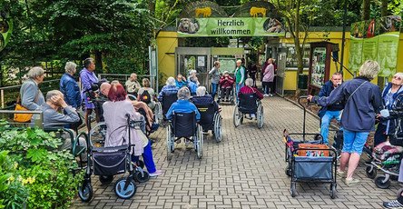 Vorfreude pur – die Senior*innen posieren gemeinsam am Zooeingang, bereit für einen erlebnisreichen Tag.