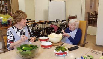 Zwei Bewohnerinnen der ProCurand Seniorenresidenz Bölschestraße bereiten gemeinsam in der Küche Gurken und Gemüse zum Einlegen vor.