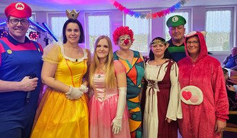 Mitarbeiter*innen der ProCurand Seniorenresidenz Am Görnsee stehen verkleidet nebeneinander und genießen gemeinsam die festliche Stimmung.