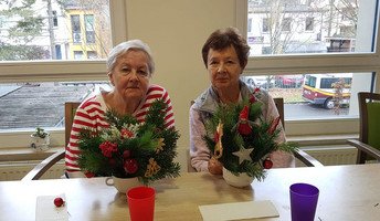 In der ProCurand Seniorenresidenz Bölschestraße sitzen zwei Bewohnerinnen an einem Tisch und gestalten gemeinsam weihnachtliche Adventsdekoration.