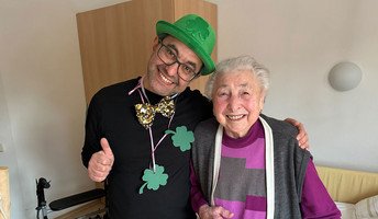 Neujahrsgruß im ProCurand Pflegestift Pfarrer Lukas in Cham: Bewohnerin mit Glücksboten Kleeblatt beim Rundgang durchs Haus.