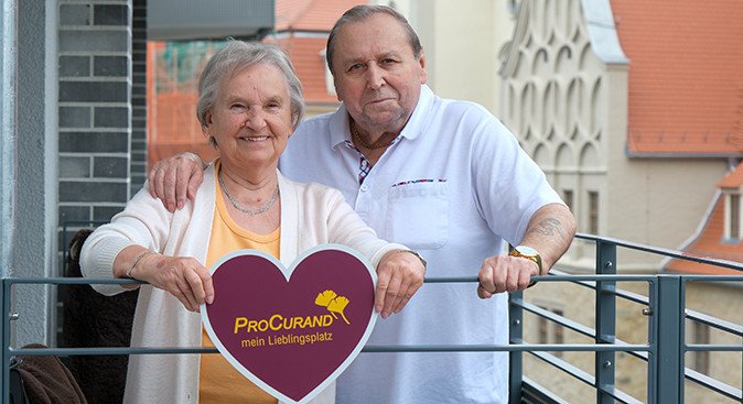 Zwei Senior*innen aus dem Service-Wohnen der ProCurand mit einem ProCurand Herz in den Händen