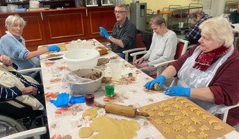 In der ProCurand Seniorenresidenz Am Görnsee backen sechs Bewohner*innen gemeinsam mit Alltagsbegleiterin Simone Karl Plätzchen und verzieren sie, darunter eine Sorte mit Amaretto.