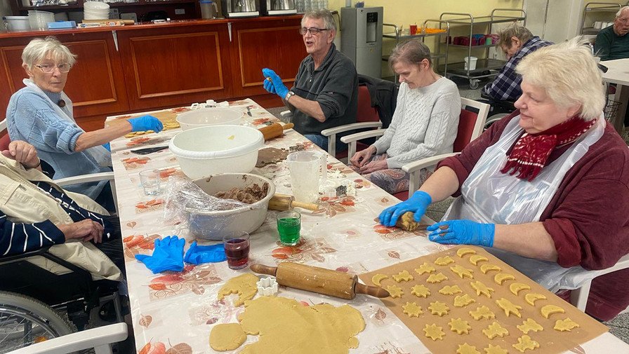 In der ProCurand Seniorenresidenz Am Görnsee backen sechs Bewohner*innen gemeinsam mit Alltagsbegleiterin Simone Karl Plätzchen und verzieren sie, darunter eine Sorte mit Amaretto.