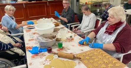 In der ProCurand Seniorenresidenz Am Görnsee backen sechs Bewohner*innen gemeinsam mit Alltagsbegleiterin Simone Karl Plätzchen und verzieren sie, darunter eine Sorte mit Amaretto.