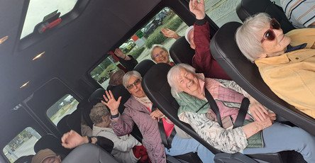 Die Gäste der ProCurand Tagespflege Strausberg sitzen gut gelaunt im Kleinbus nach Oderberg, lachen und heben voller Freude die Hände in die Luft.