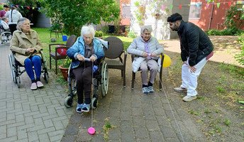 Im Garten der ProCurand Seniorenresidenz Havelpalais ziehen zwei Seniorinnen beim Spiel „Enten aufwickeln“ mit viel Geschick die Bälle an einem Seil zu sich.