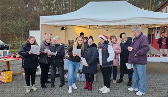 Weihnachtsmarkt vor der ProCurand Seniorenresidenz Am Görnsee in Grebs mit Bewohnerinnen, Angehörigen und Nachbarinnen. DJ Percy Assmann spielt, das Team singt Weihnachtslieder und alle genießen Leckereien wie Kuchen, Glühwein und Waffeln.