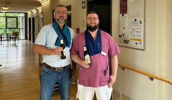 Einrichtungsleiter Enrico Hennig (links) und Mitarbeiter Patrick (rechts) halten kühle Getränke in der Hand, um das Team der ProCurand Seniorenresidenz Havelpalais an heißen Tagen zu erfrischen.