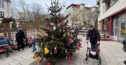Ein glücklicher Senior in der ProCurand Seniorenresidenz bewundert den prachtvoll geschmückten Weihnachtsbaum.
