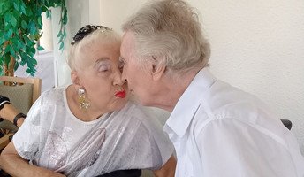 Das Ehepaar Riebisch küsst sich während des Grillfests in der ProCurand Seniorenresidenz Am Straussee und genießt die ausgelassene Stimmung.