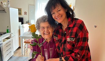 Pflegedienstleitung Andrea Liebner übergibt Seniorin der  Seniorenresidenz Bölschestraße eine gelbe Rose zum Weltfrauentag.