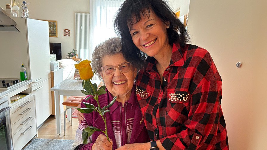 Pflegedienstleitung Andrea Liebner übergibt Seniorin der  Seniorenresidenz Bölschestraße eine gelbe Rose zum Weltfrauentag.