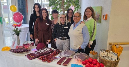 Im Eingangsbereich der ProCurand Seniorenwohnanlage Fideliswiesen stehen sieben Kolleginnen, darunter das Leitungsteam, hinter einem Infotisch mit Materialien und Give-aways.