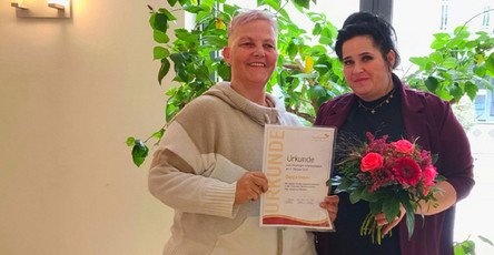 In der ProCurand Seniorenresidenz Park Sanssouci überreicht Pflegedienstleitung Manuela Grund ihrer Kollegin Dunja Hoyer zum 20-jährigen Dienstjubiläum eine Urkunde und einen Blumenstrauß.