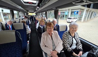 Im Bus sitzt die fröhliche Reisegruppe aus der ProCurand Residenz Am Hallorenring, die sich auf den gemeinsamen Ausflug nach Berlin freut.