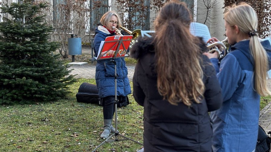 Im Vorgarten der ProCurand Seniorenresidenz Bölschestraße spielen Petra Rattmann und der Bläserchor der evangelischen Grundschule Friedrichshagen weihnachtliche Lieder für die Bewohner*innen.