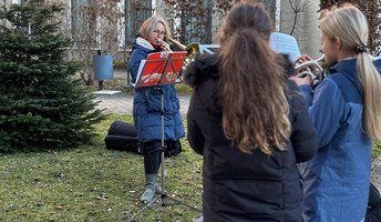 Im Vorgarten der ProCurand Seniorenresidenz Bölschestraße spielen Petra Rattmann und der Bläserchor der evangelischen Grundschule Friedrichshagen weihnachtliche Lieder für die Bewohner*innen.