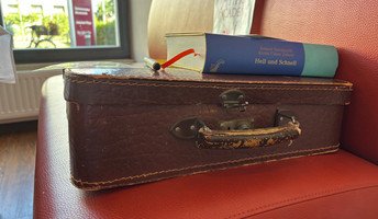 Ein Bücherkoffer mit einem aufgelegten Buch steht im Restaurant Vier Jahreszeiten der ProCurand Seniorenresidenz Bölschestraße.