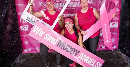 Stolze Muddy Angels – Vanessa, Denise und Isabelle zeigen ihre Startschilder und strahlen voller Vorfreude auf den Schlammlauf.