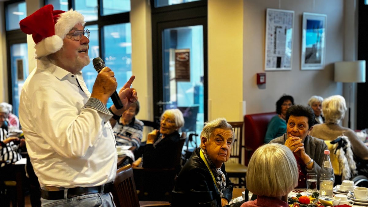 Musikalische Unterhaltung bei der Weihnachtsfeier in der ProCurand Seniorenresidenz Bölschestraße: Alf Weis singt, begleitet von Gitarrist Sebastian Grytzka, viele Bewohner*innen hören zu und singen mit.