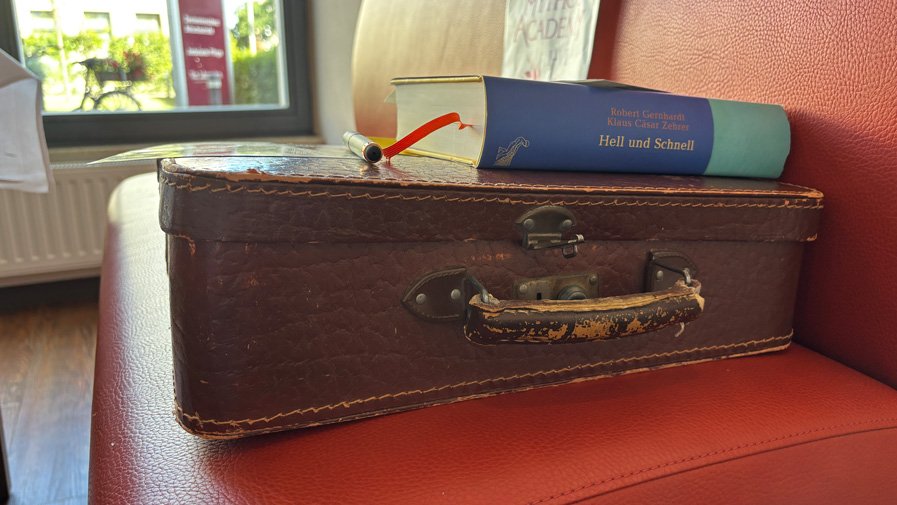 Ein Bücherkoffer mit einem aufgelegten Buch steht im Restaurant Vier Jahreszeiten der ProCurand Seniorenresidenz Bölschestraße.