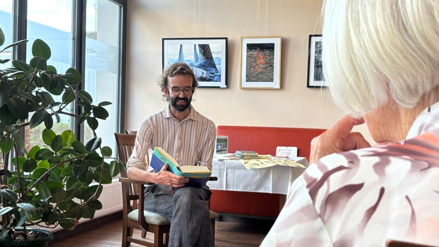 Christoph Berger liest im Restaurant Vier Jahreszeiten der ProCurand Seniorenresidenz Bölschestraße einer kleinen Runde von Bewohner*innen vor.