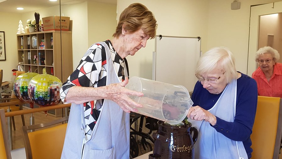Nachdem das Gefäß gefüllt ist, gießen Seniorinnen in der ProCurand Seniorenresidenz Bölschestraße die vorbereitete Flüssigkeit über die Gurken.