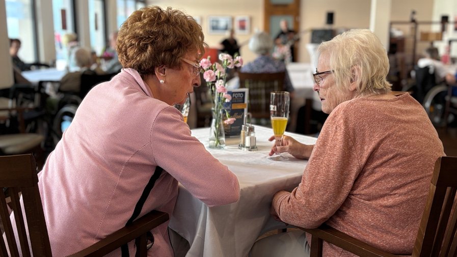 Bewohner*innen und Gäste genießen in der ProCurand Seniorenresidenz Bölschestraße bei Kuchen und Getränken die Musik von Lovelysoul.