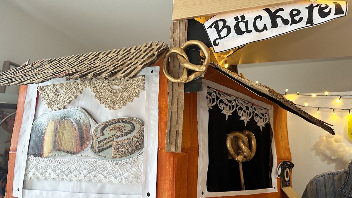 Die selbstgebaute Puppenbühne ist zu sehen. Vor der Bühne sind Dekorationselemente und Requisiten platziert, die für die Aufführung vorbereitet wurden.