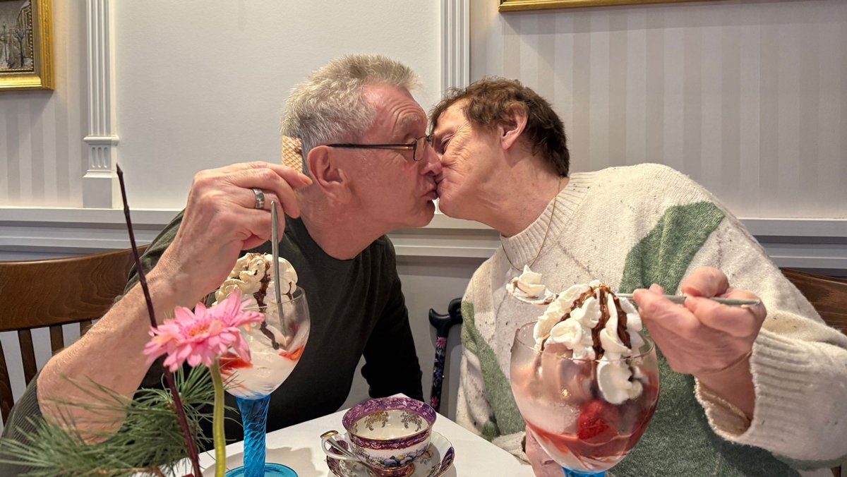 Zwei Bewohner*innen teilen einen liebevollen Moment bei Kaffee und Dessert während des Ausflugs nach Golzow.