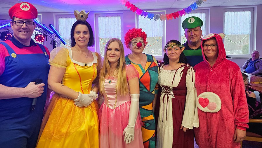 Mitarbeiter*innen der ProCurand Seniorenresidenz Am Görnsee stehen verkleidet nebeneinander und genießen gemeinsam die festliche Stimmung.