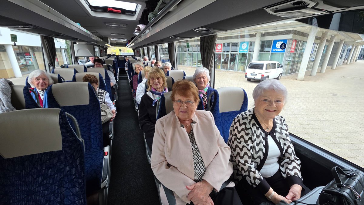 Im Bus sitzt die fröhliche Reisegruppe aus der ProCurand Residenz Am Hallorenring, die sich auf den gemeinsamen Ausflug nach Berlin freut.