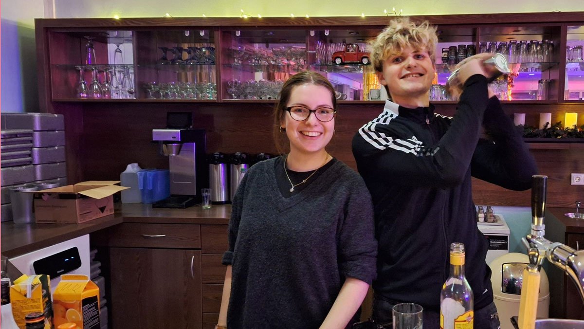 Joshua Groh und Jasmina Pehns mixen Cocktails hinter dem Tresen im Café Havelblick der ProCurand Seniorenresidenz Havelpalais.