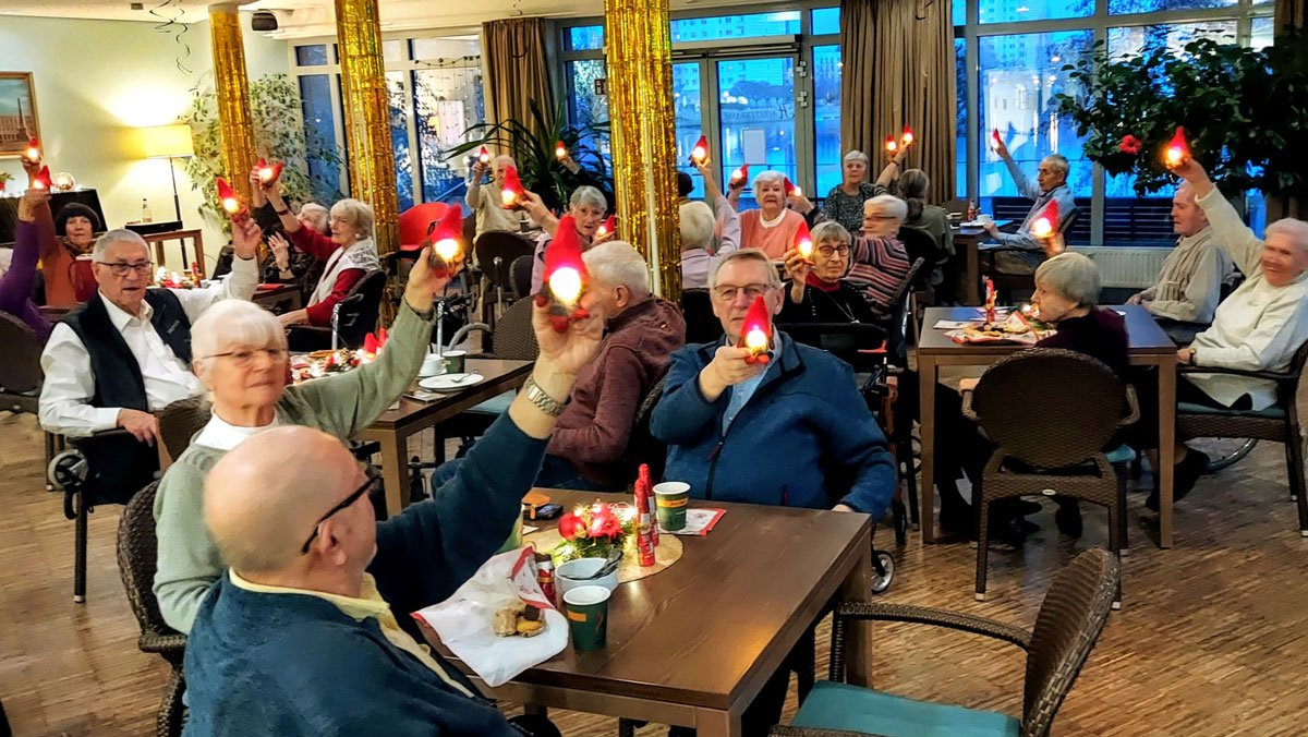  Bewohner*innen und Mieter*innen aus dem Service-Wohnen feiern gemeinsam im Café Havelterrasse der ProCurand Seniorenresidenz Havelpalais und erhalten leuchtende Wichtel.