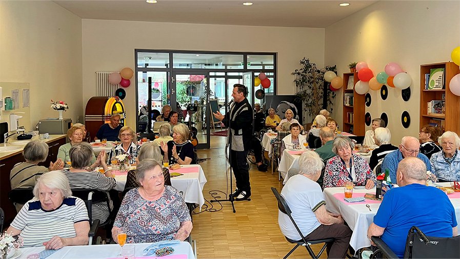 In der ProCurand Seniorenresidenz Park Sanssouci in Potsdam sorgt Sänger Dirk Jüttner für Stimmung: Die Senior*innen genießen an dekorierten Tischen die Hits der 50er und 60er Jahre.