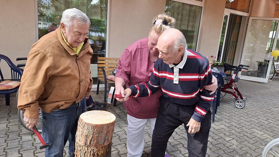 Mit viel Freude und Geschick schlagen die Bewohner der ProCurand Seniorenresidenz Senftenberg Nägel in einen Baumstumpf – handwerkliches Talent war gefragt!