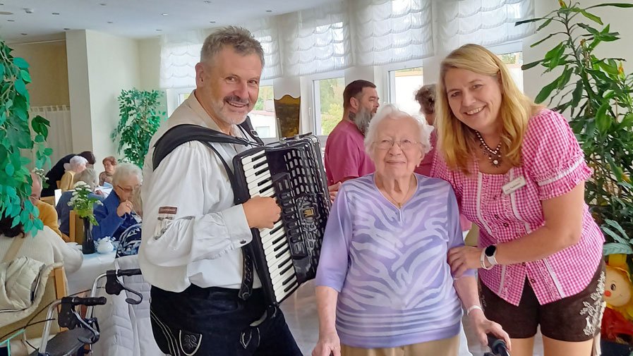 Musiker, Seniorin und Einrichtungsleitung beim  Oktoberfest in der ProCurand Seniorenresidenz Am Straussee 