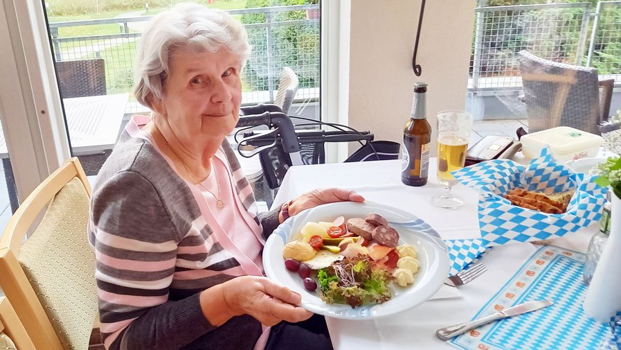 Seniorin mit zünftigem Oktoberfestmenü in der ProCurand Seniorenresidenz Am Straussee