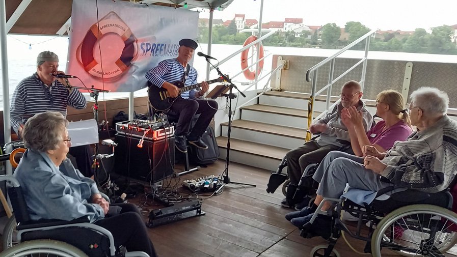 Die Gruppe ist auf der Fähre, singt fröhlich mit den „Spreematrosen“ und schunkelt, während die Sonne den See glitzern lässt – ein unvergesslicher Ausflug voller Musik und guter Laune.