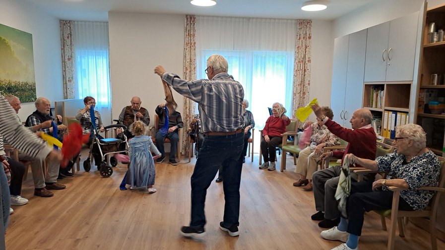 In der ProCurand Tagespflege Strausberg tanzen Senior*innen fröhlich mit den kleinen Besucher*innen durch den Raum – eine besondere Begegnung voller Lebensfreude.