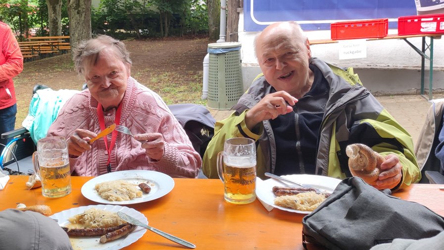 Beim Genießen der Mahlzeit lassen sich die Bewohner*innen des ProCurand Seniorenzentrums Am Herzogschloss die Bratwürste mit Sauerkraut schmecken und genießen das Fest mitten auf dem Stadtberg.