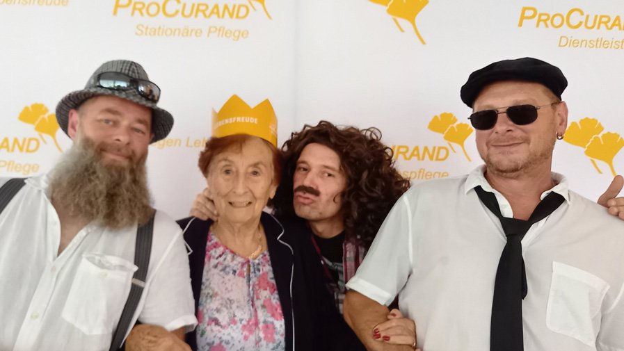 Bewohner*innen und Mitarbeitende machen lustige Selfies zusammen, lachen herzlich und halten die fröhlichen Sommerfestmomente für die Ewigkeit fest.